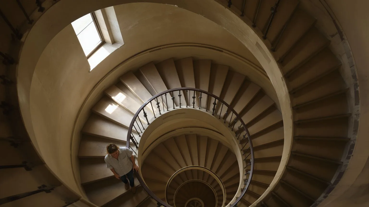 Person paused on spiral staircase viewed from above illustrating repeating spiritual crisis loop