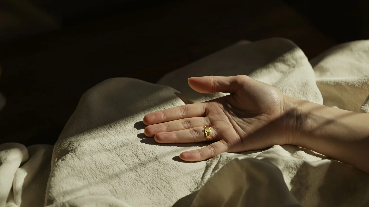 Close-up of unclenching hand on linen surface showing what shadow work in spirituality feels like in the body