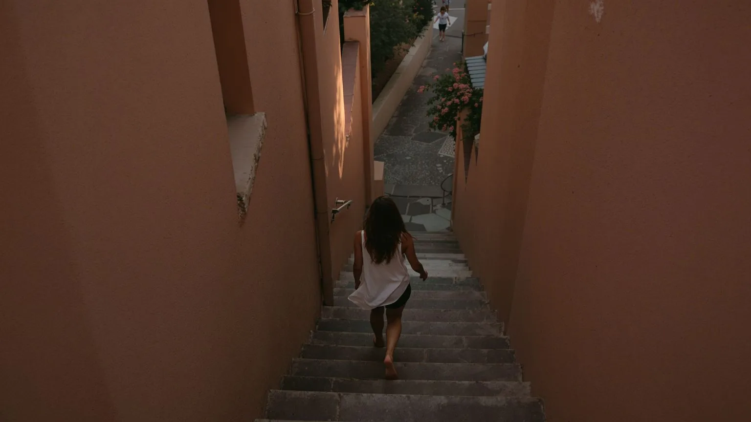 Woman walking barefoot down stone steps at dusk in a body-grounded practice for shadow work