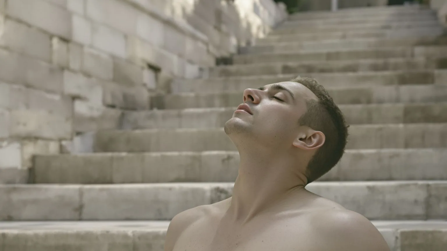 Man with relaxed throat and neck on stone steps in morning light showing what changed and softened through somatic yoga