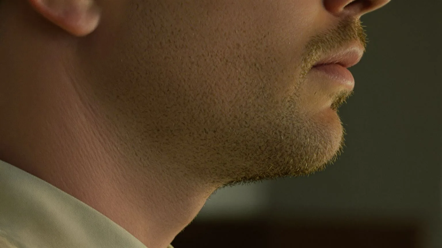 Close-up of a man's tense jaw and neck showing where the body speaks first through held tension Close-up of a man's tense jaw and neck showing where the body speaks first through held tension