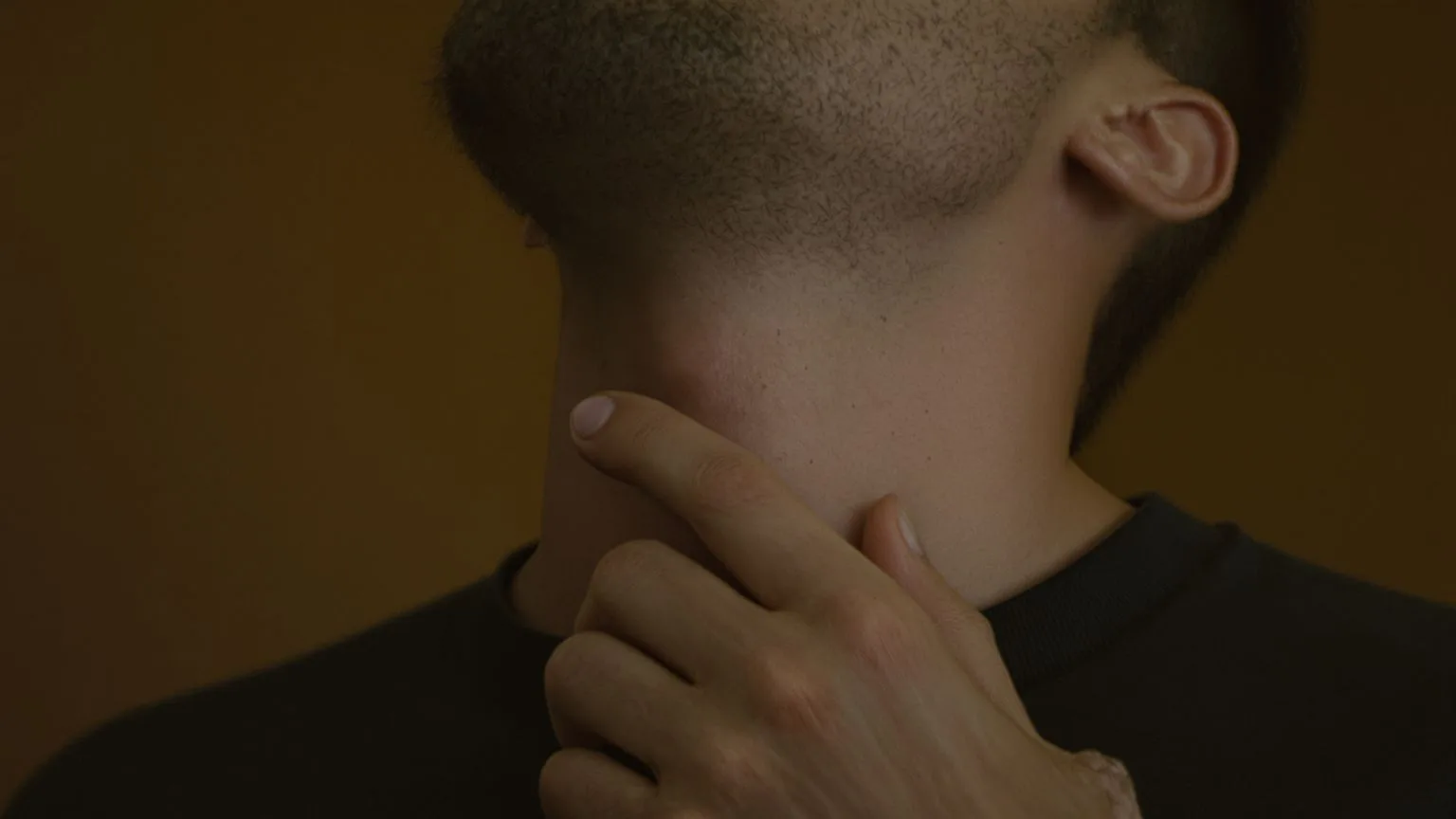 Close-up of man's hand near throat and neck showing body tension when mind says nobody cares