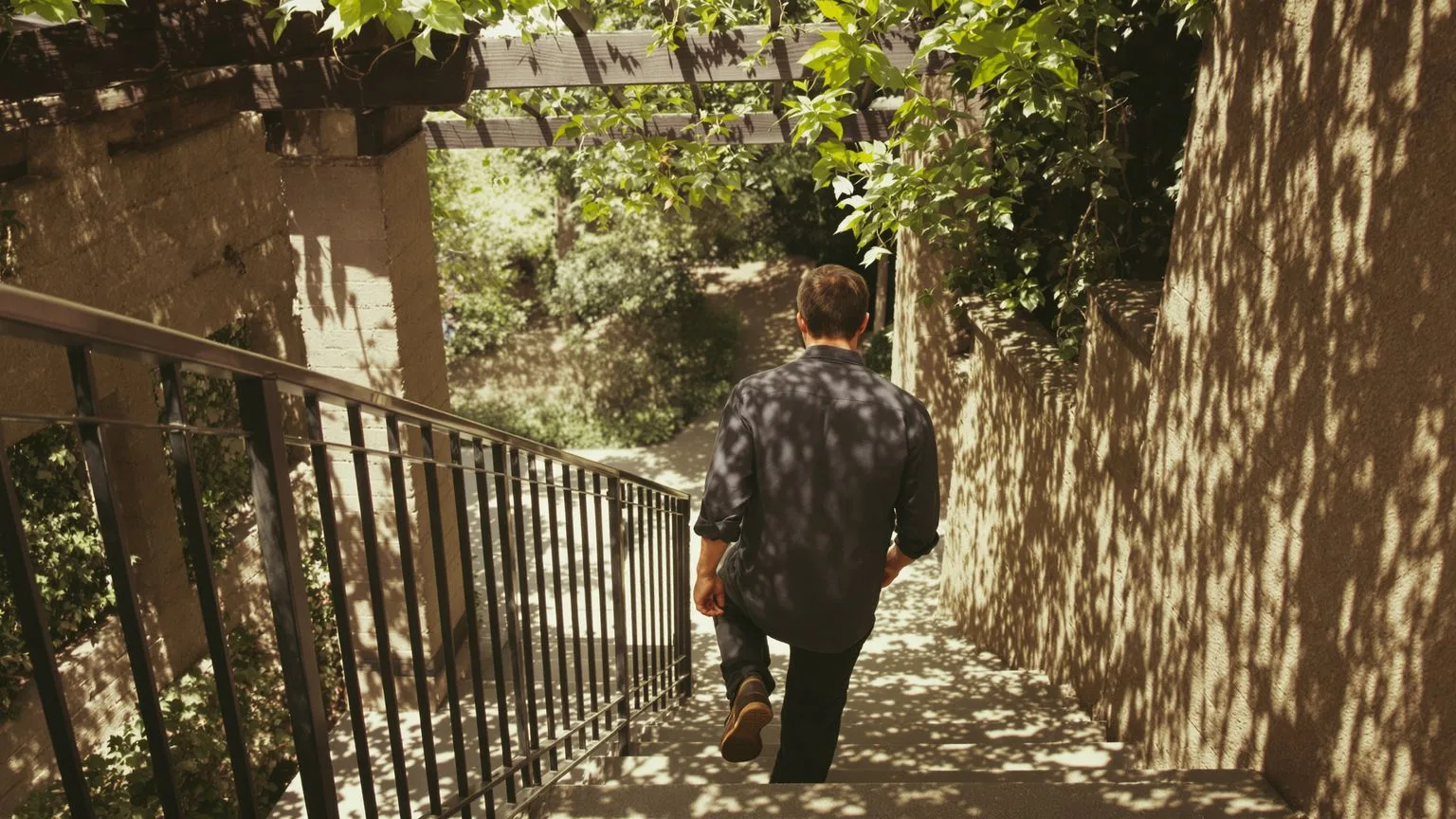 Man hesitating at top of stone steps leading to sunlit path showing body tension between resistance Man hesitating at top of stone steps leading to sunlit path showing body tension between resistance and permission