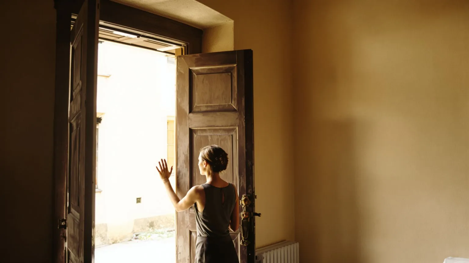 Woman standing in open doorway with hand on frame showing the mask worked but dropping it feels scary