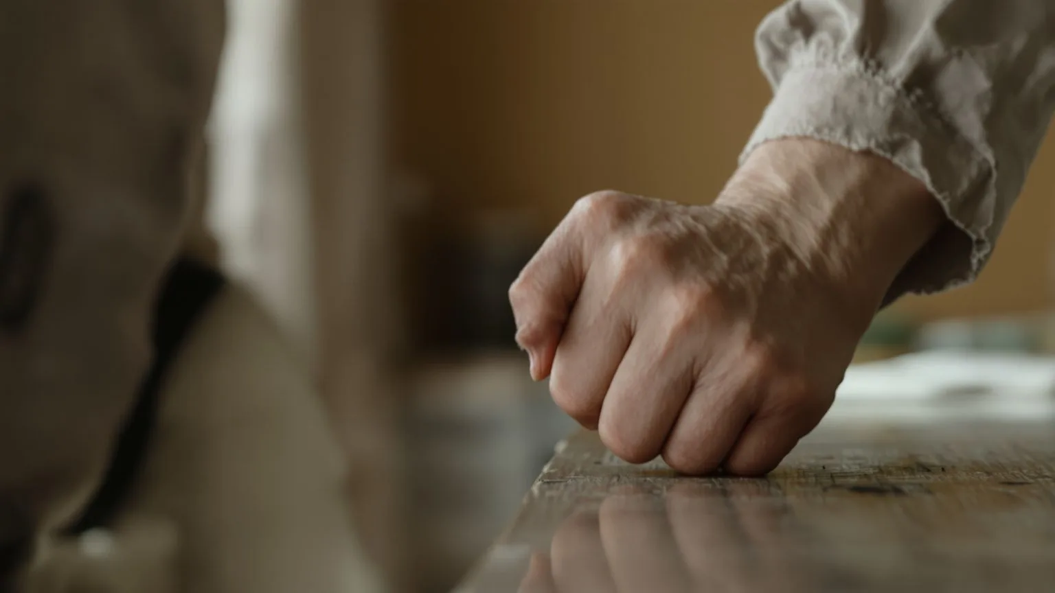 Close-up of tense hands gripping desk edge showing where emotional suppression lives in the body Close-up of tense hands gripping desk edge showing where emotional suppression lives in the body