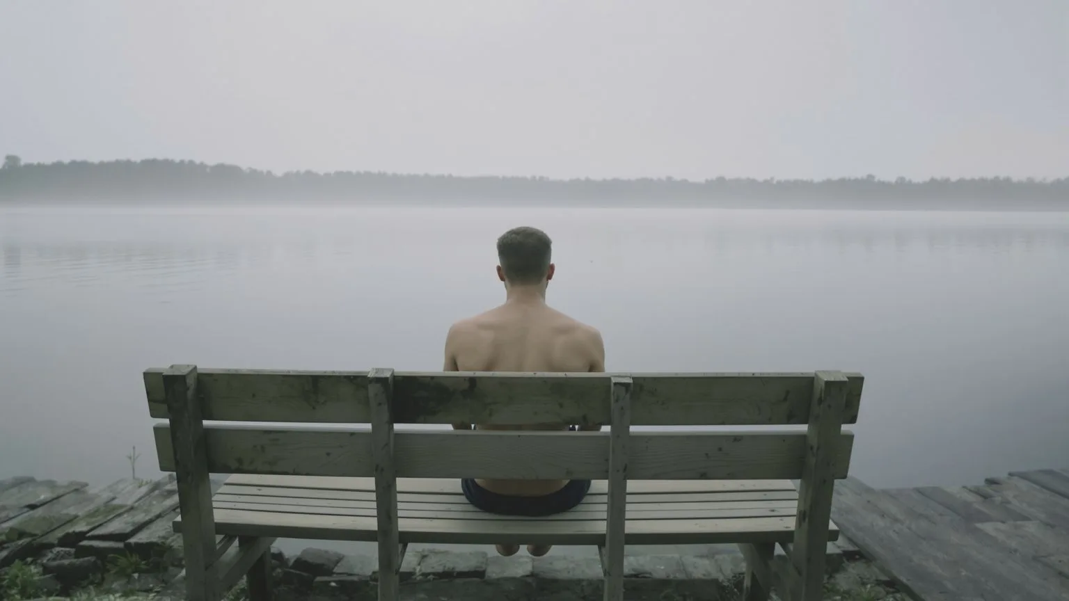 Man's back and posture releasing tension on lakeside bench showing link between suppressing emotions Man's back and posture releasing tension on lakeside bench showing link between suppressing emotions and physical symptoms