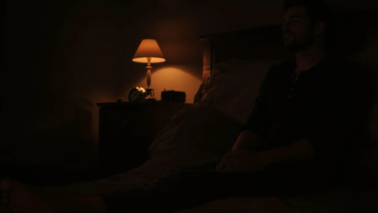 Person sitting on bedroom floor at night grounding the body after emotional wave from massage