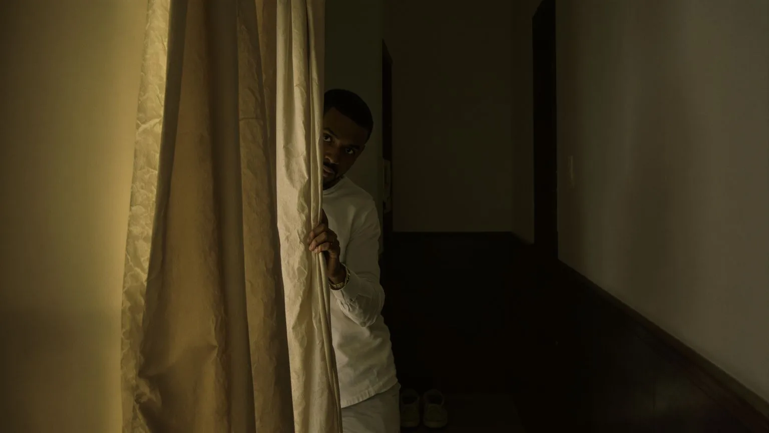 Man stepping through a curtained hallway toward light, embodying the clear next step forward