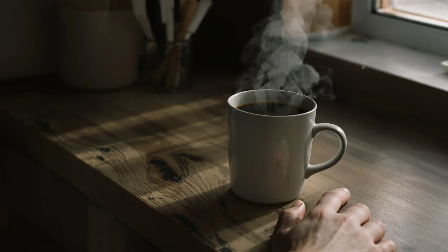 Untouched coffee mug and curled hand on kitchen counter showing subtle signs of emotional suppressio Untouched coffee mug and curled hand on kitchen counter showing subtle signs of emotional suppression