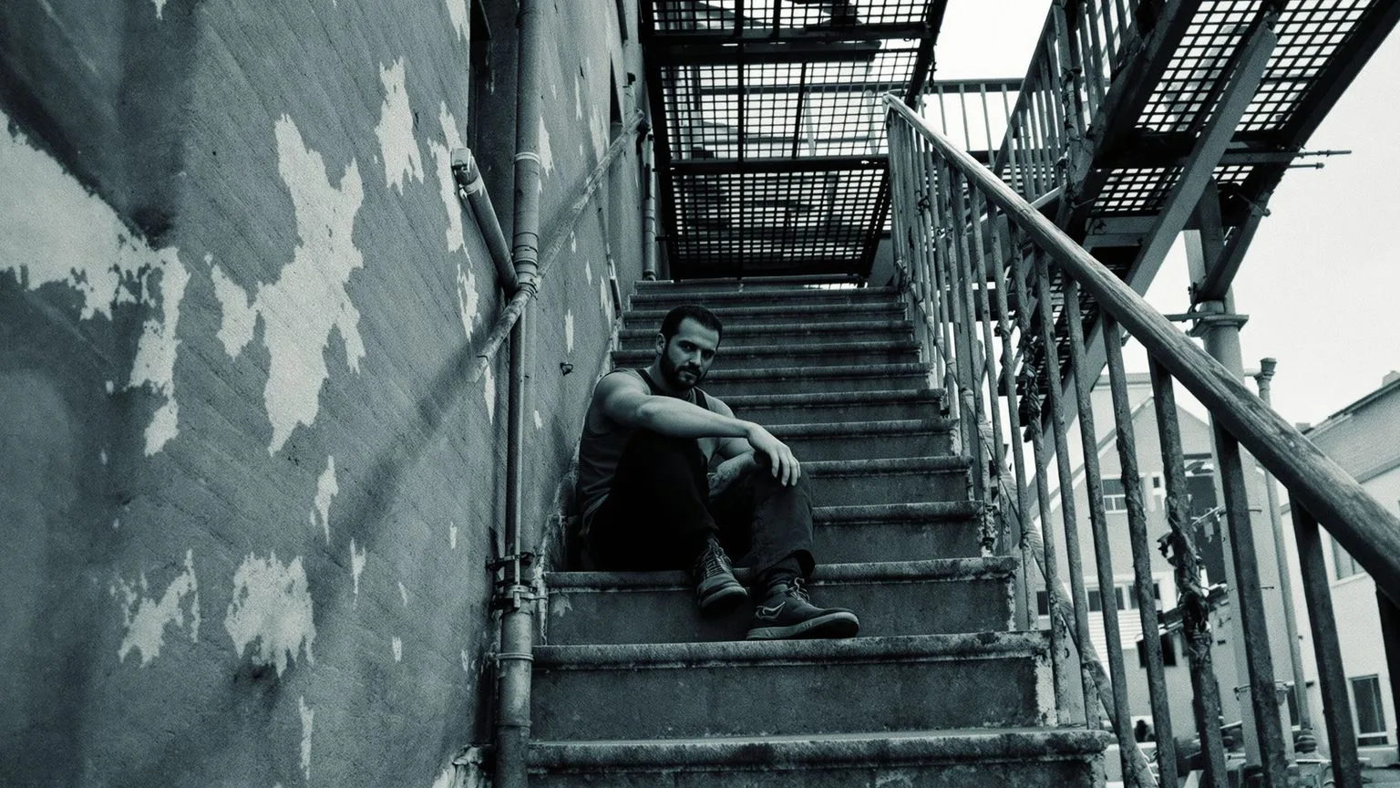 Overhead view of woman curled on linen bed wondering why can't I cry as rain falls on skylight above