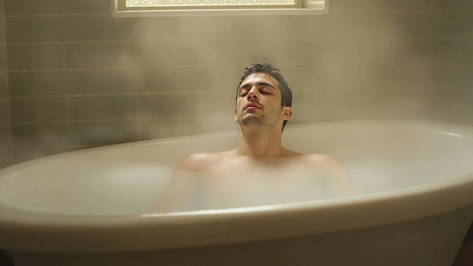Man with eyes closed in a deep bathtub with steam rising, feeling lost in life finally pausing