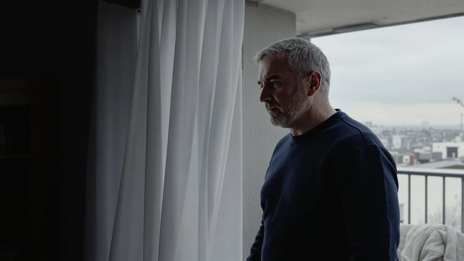 Man standing at balcony doorway threshold between shadow and light exploring the wound beneath the wound