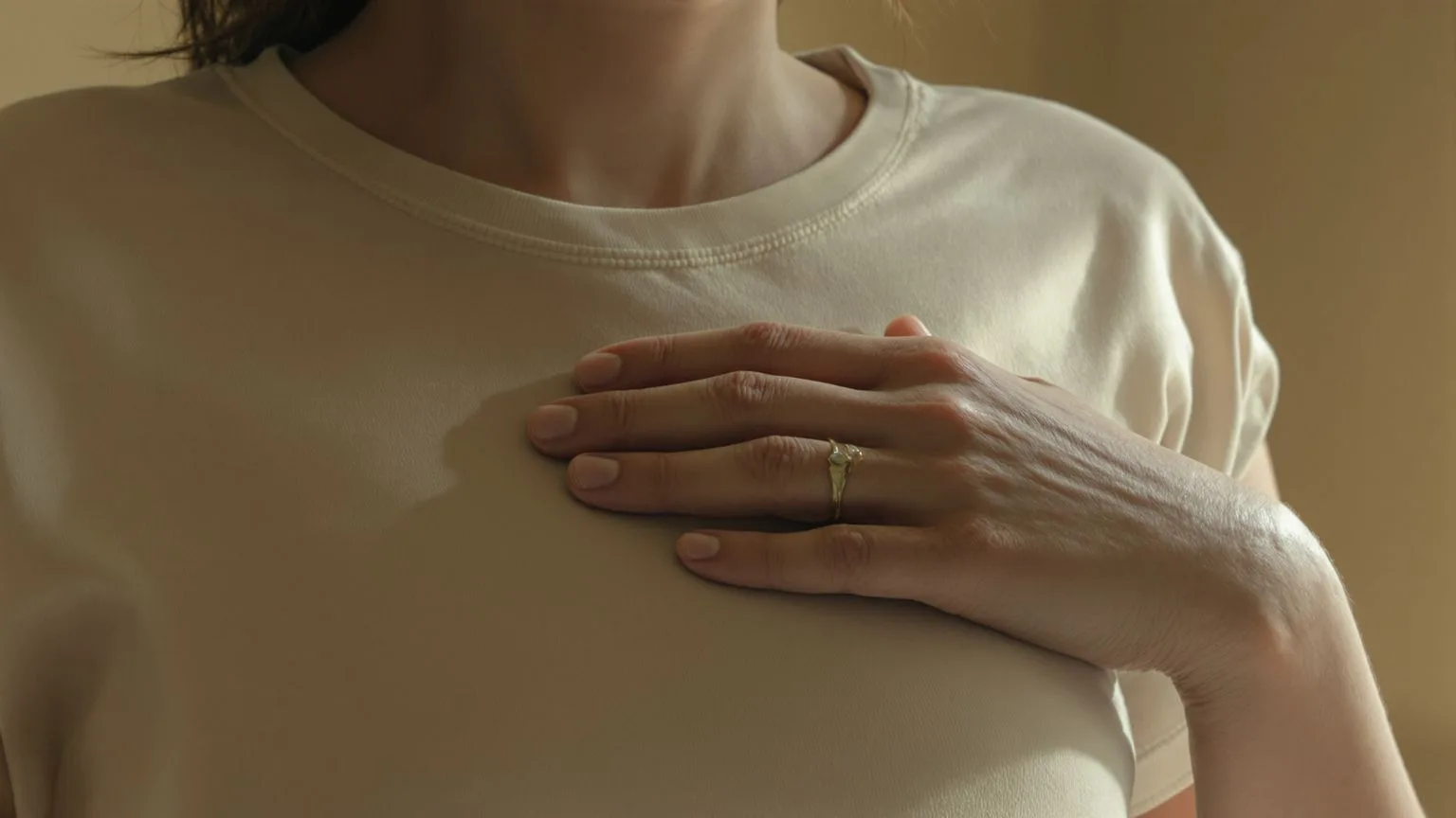 Close-up of a hand pressed against the upper chest showing where emotional numbness lives in the body