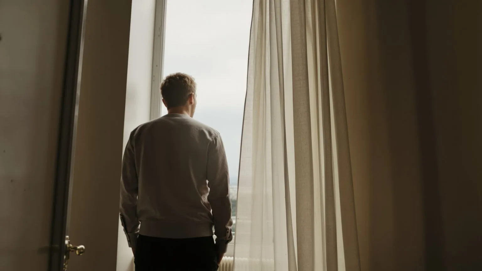 Person standing at window in contemplative moment, learning how to practice self-love through accept Person standing at window in contemplative moment, learning how to practice self-love through acceptance